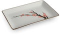 Mierne z boku fotený obdĺžnikový porcelánový tanier na sushi z kolekcie Sakura s rozmermi 20x13cm. Na hladkom bielom podklade vyniká asymetrická, ručne maľovaná vetvička s ružovými kvetmi japonskej čerešne. Tanier má jemne zaoblené rohy a kontrastný hnedý