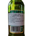 Detailný záber na zadnú stranu zelenej sklenenej fľaše čínskeho piva Tsingtao (330 ml). Biela slovenská informačná etiketa uvádza presné zloženie (voda, jačmenný slad, ryža, chmeľ), obsah alkoholu 4,7 % vol., krajinu pôvodu Čína a údaje o dovozcovi SOFTEL