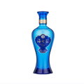 Priamy pohľad na elegantnú modrú sklenenú fľašu čínskeho prémiového destilátu Yanghe Spirit Classic s názvom Ocean Blue (Hai Zhi Lan). Fľaša má tvar pripomínajúci kvapku vody s prepracovanými zlatými detailmi a tradičným čínskym písmom na tmavomodrej etik