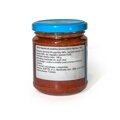 Zadná strana skleneného pohára s jemne pálivou paprikovou omáčkou Harissa s hmotnosťou 190 g. Detailný pohľad na slovenskú etiketu, ktorá uvádza zloženie: 56 % červené čili papričky, 24 % červená paprika a 10 % cesnak. Etiketa obsahuje aj informáciu o kra